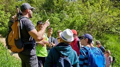 A guide leading a group of hikers along a wooded trail