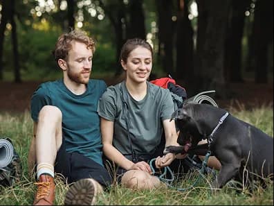 A couple sitting in the woods with their dog