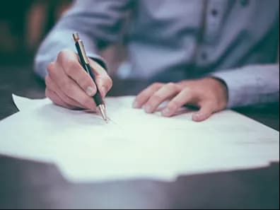 A person writing on paper at a desk
