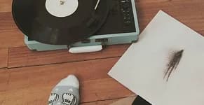 A record player and a feather on a wooden floor.