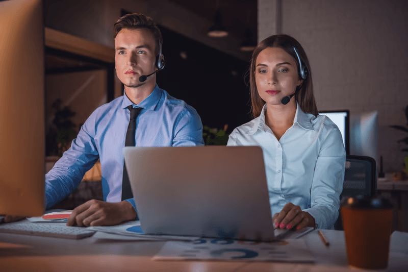 Two support agents wearing headsets at their desks