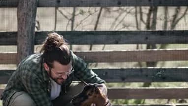 A man petting a dog beside a wooden fence