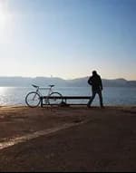A person standing by a lake beside a parked bicycle