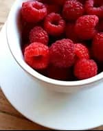 A bowl of raspberries on a table