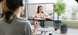 A woman on a video session with a therapist at her desk