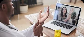 A man gesturing during a video session on a laptop