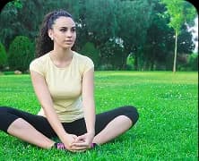A woman sitting cross-legged on the grass in a park