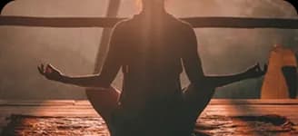 A person meditating at sunset