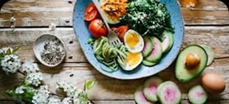 A bowl of salad, eggs and avocado on a wooden table